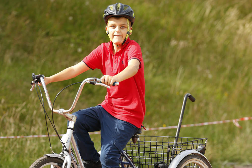 A boy riding a three-wheeled adapted bike