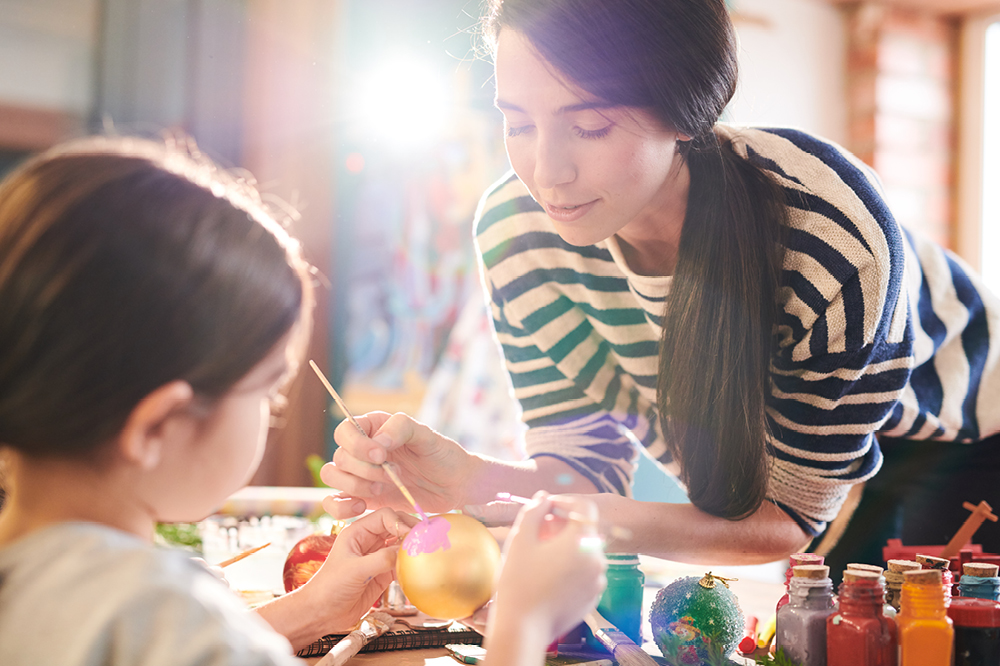 A woman doing crafts with a child on a sunny day