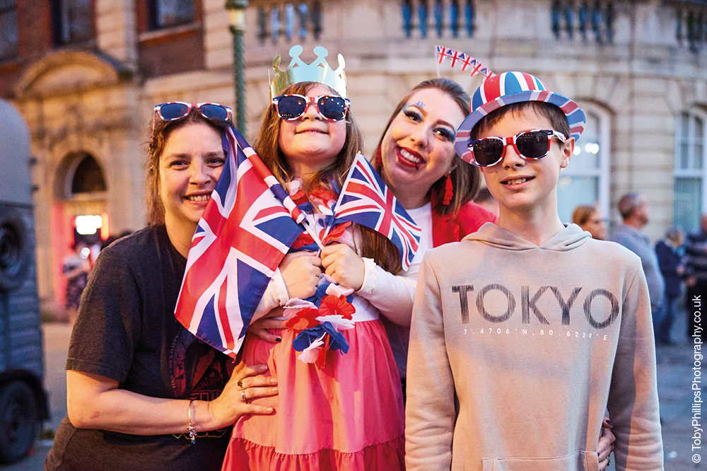 Two women, a boy and a girl holding union flags and smiling