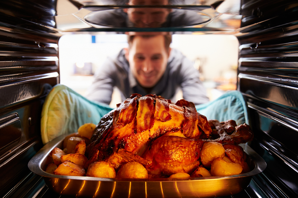 Man putting turkey into the oven