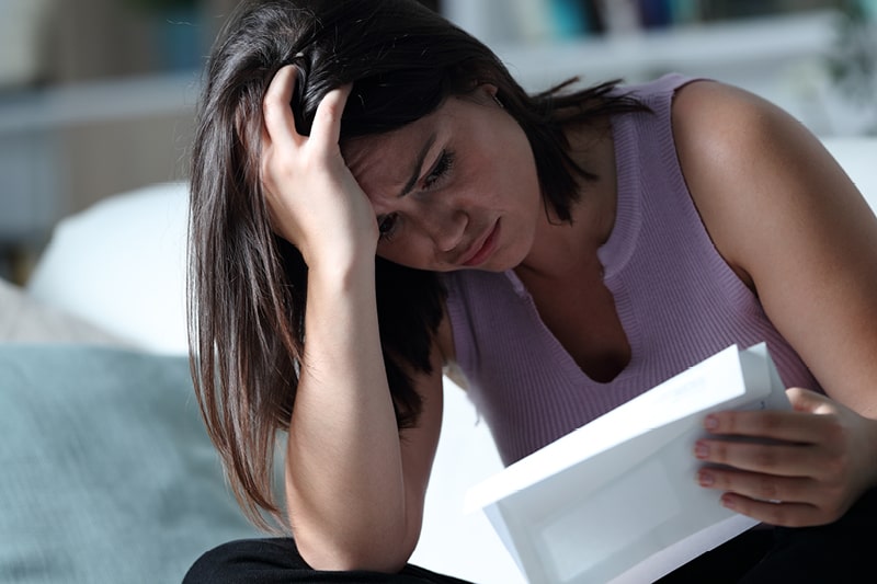 A woman looks sadly at a paper bill