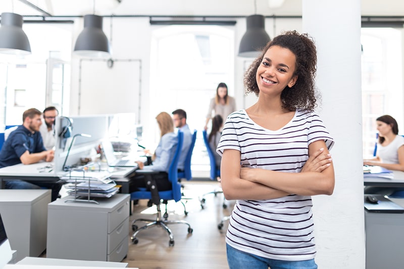 A woman smiles in an open-plan modern office