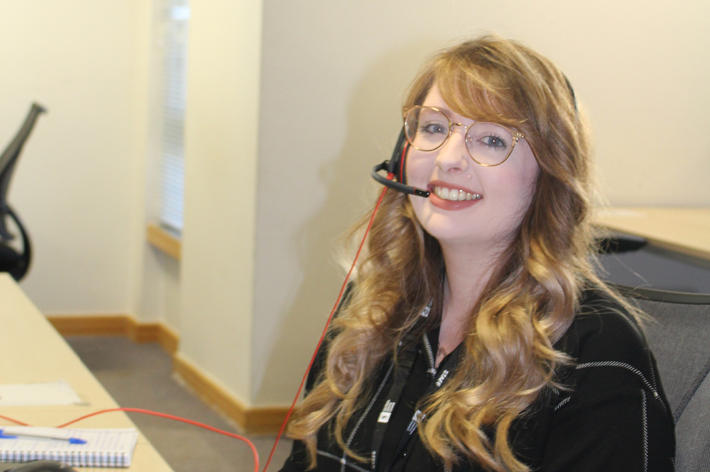 A woman smiling and wearing a headset