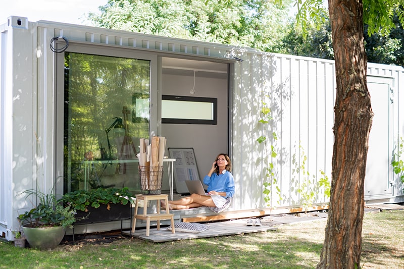Woman sat outside their converted home office in the garden