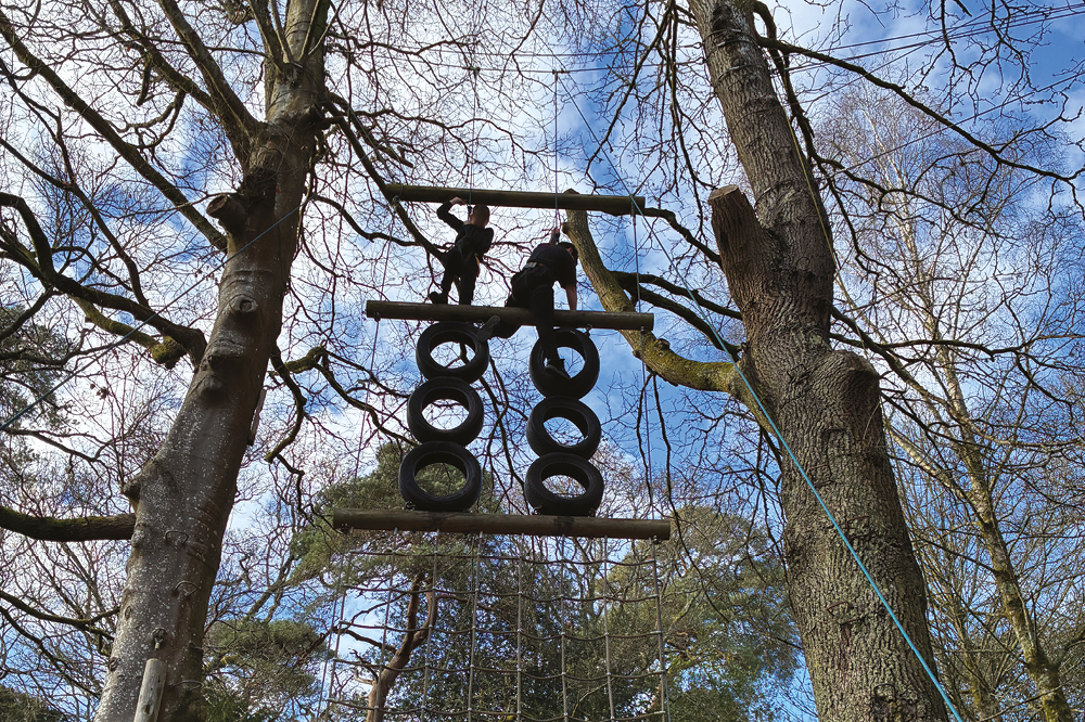 Lodge Hill climbing activity with two young people participating in a woodland tree-level climbing activity